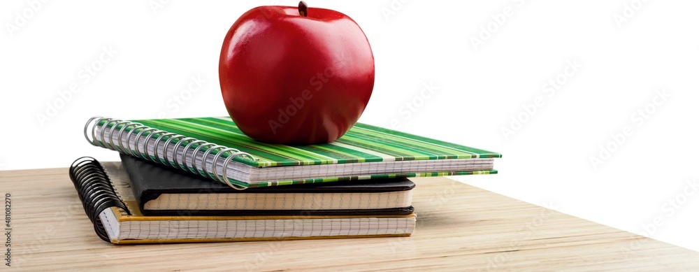 School teachers desk with stack of books and apple