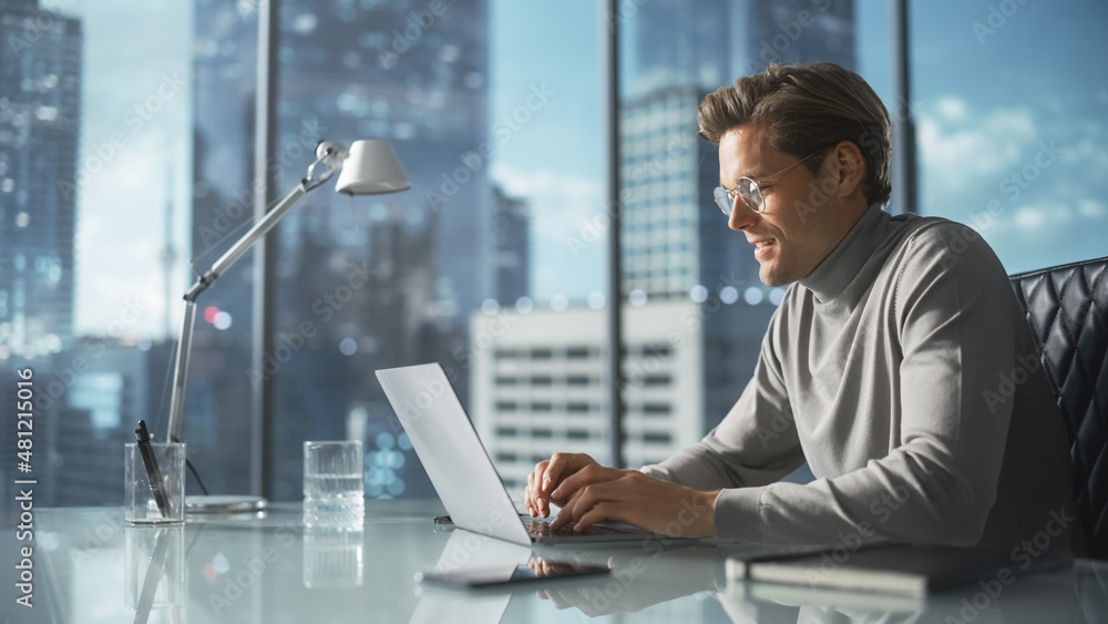 Creative Businessman in a Turtleneck Jumper Sitting in Modern Office, Using Laptop Computer Next to 