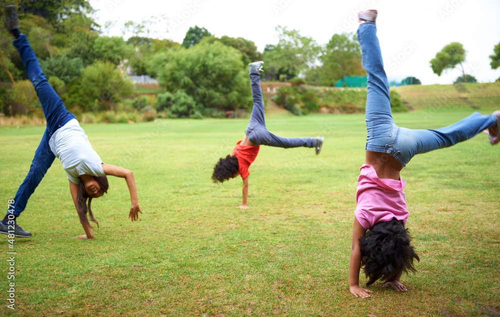 Cartwheel fun. Three young children doing handstands in the park.