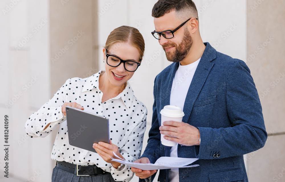 Smiling business colleagues dressed in formal clothes discussing work while standing outside