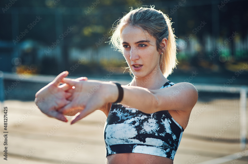 Prepping with some stretches. Shot of a sporty young woman stretching her arms while exercising on a