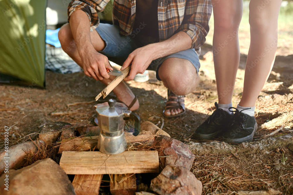 Putting on the morning coffee. Shot of campers preparing a campfire to make coffee.