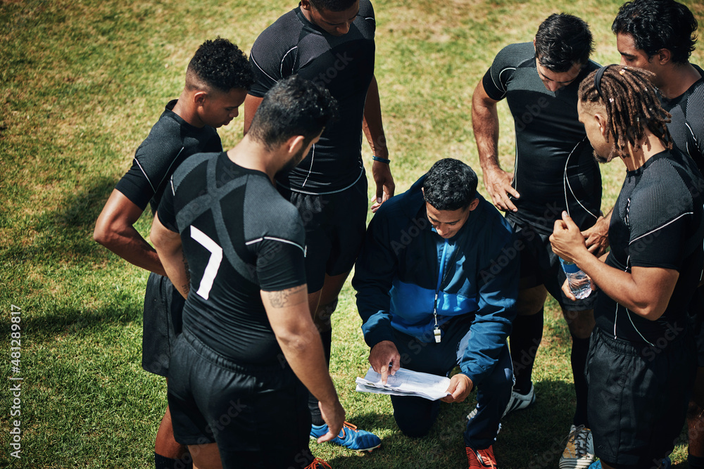 So heres the plan. High angle shot of a handsome young rugby coach addressing his team on the field