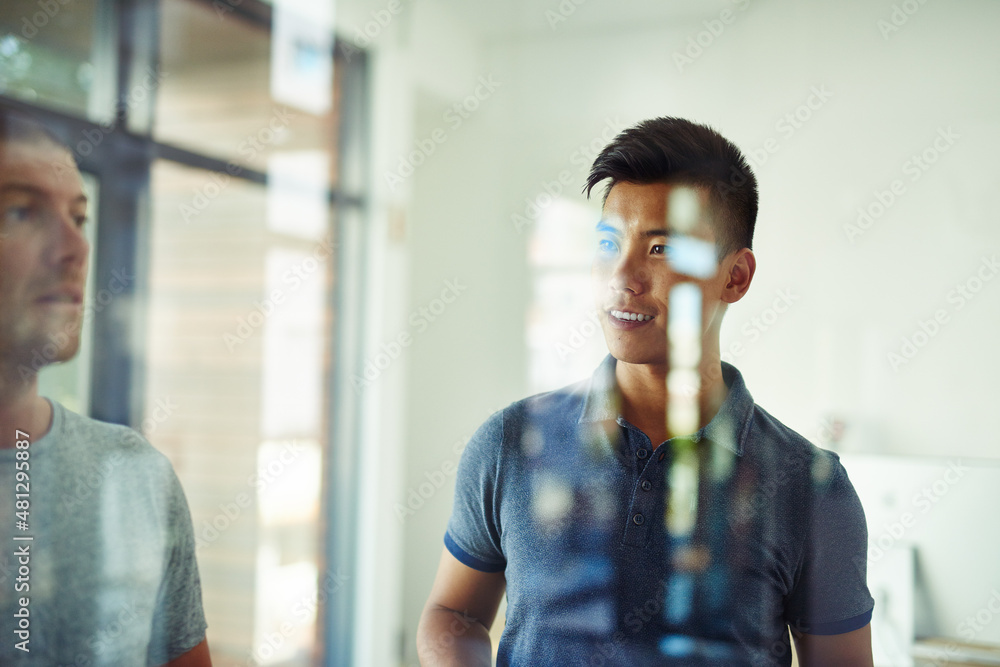 Planning is the first step. Cropped shot of a group of young designers planning on a glass board.