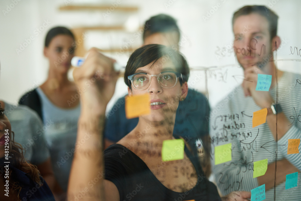 Planning is the first step. Cropped shot of a group of young designers planning on a glass board.