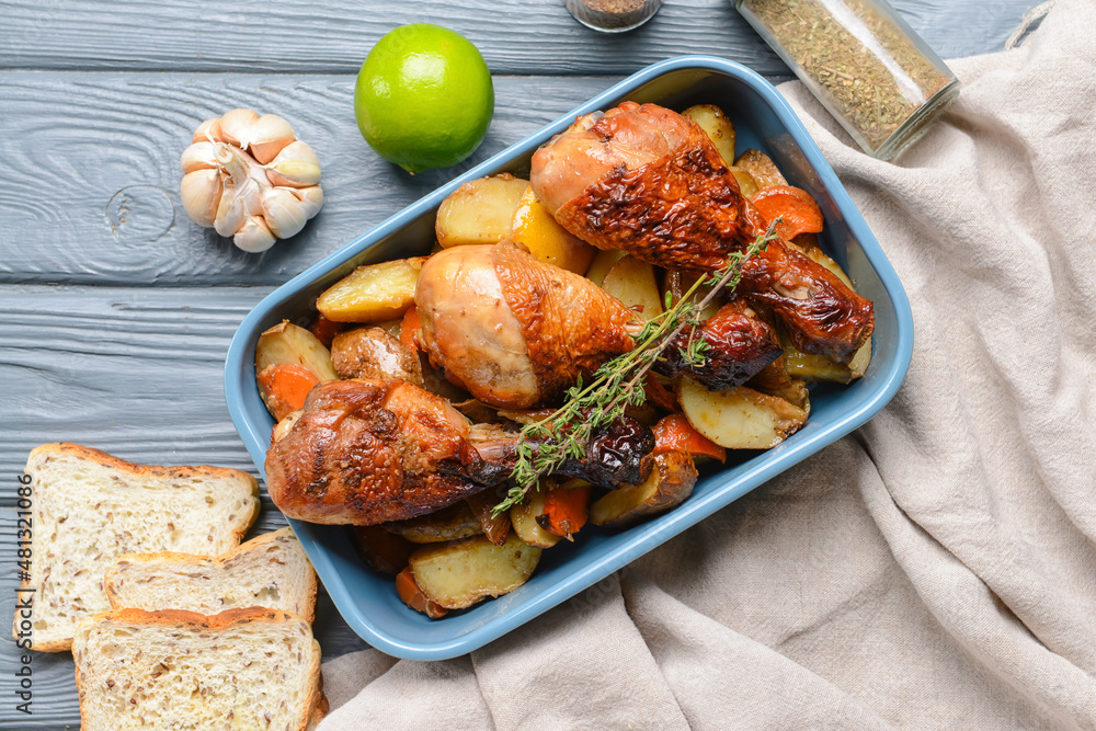 Baking dish with tasty cooked chicken drumsticks and potatoes on table