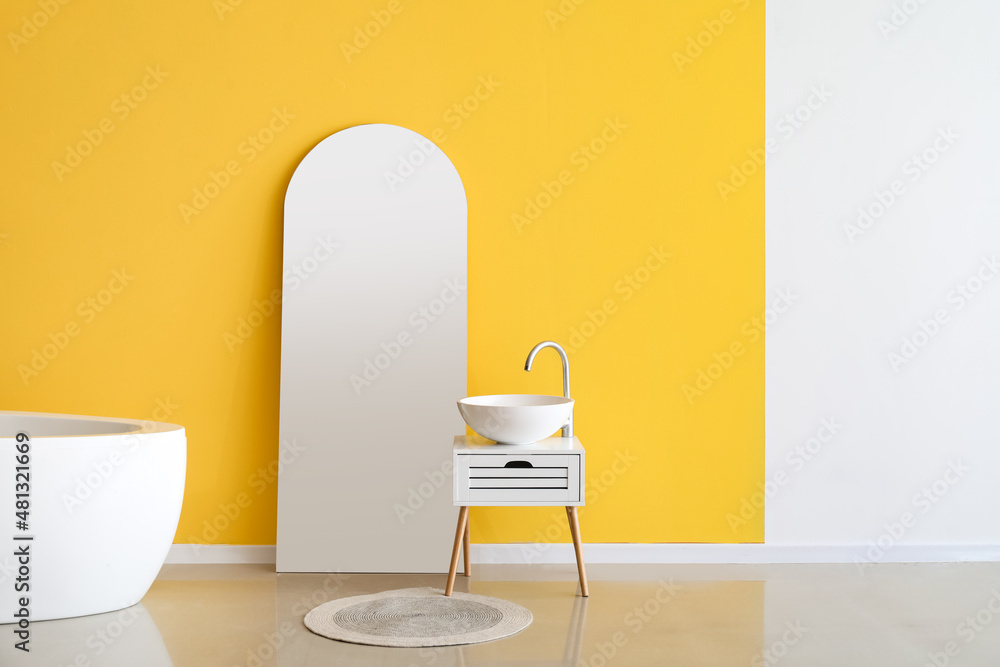 Stylish mirror and sink near color wall in bathroom