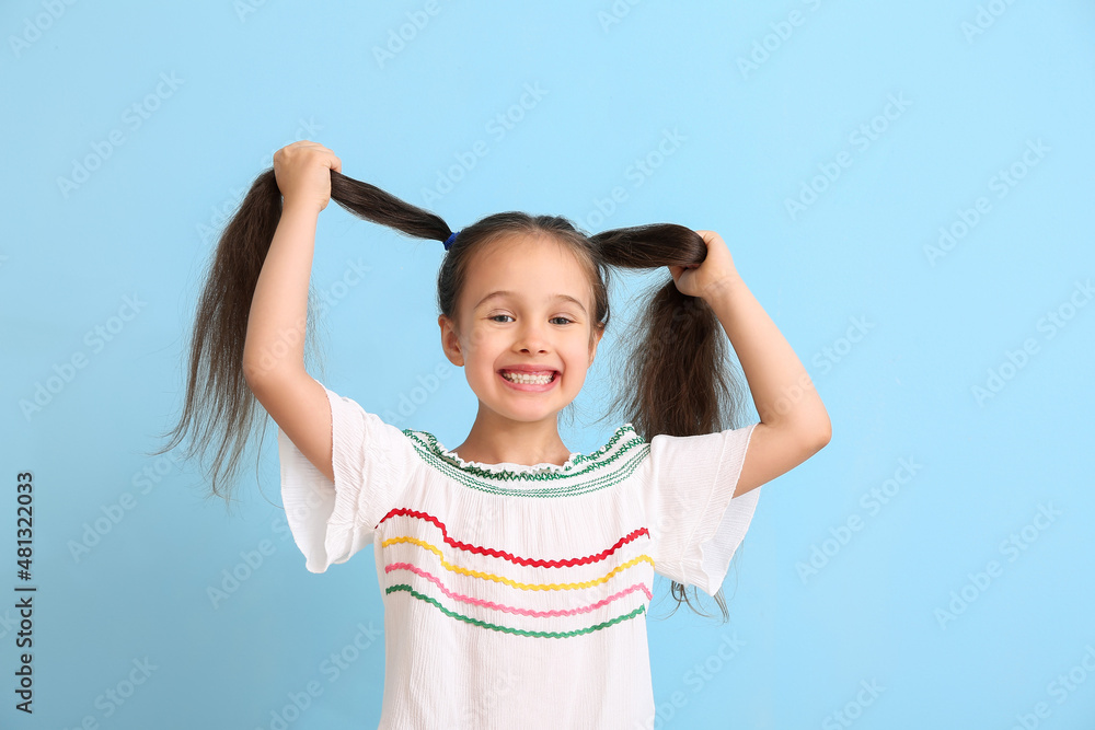 Portrait of happy little girl with ponytails on blue background