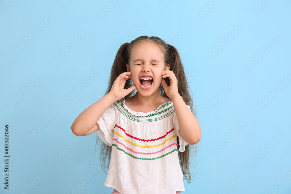 Portrait of angry little girl with ponytails on blue background