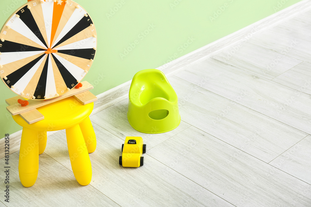 Potty, toy car and table with wheel of fortune on grey wooden floor