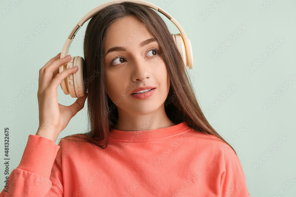 Cool young woman listening to music on color background