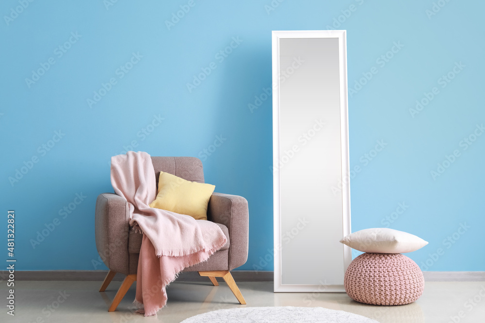 Interior of room with armchair and mirror near color wall