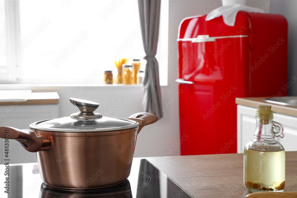 Bottle of oil and cooking pot on stove in kitchen