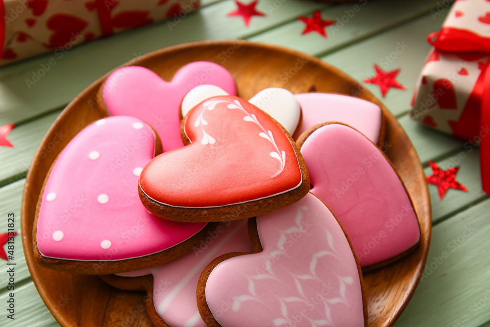 Plate with tasty heart shaped cookies on green wooden background, closeup