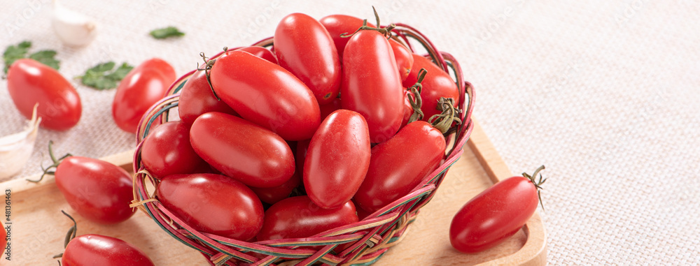 Fresh cherry tomatoes in a basket with spices.