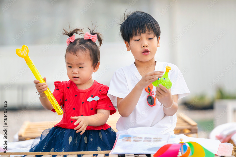 asian little girl and boy playing with toys by at home