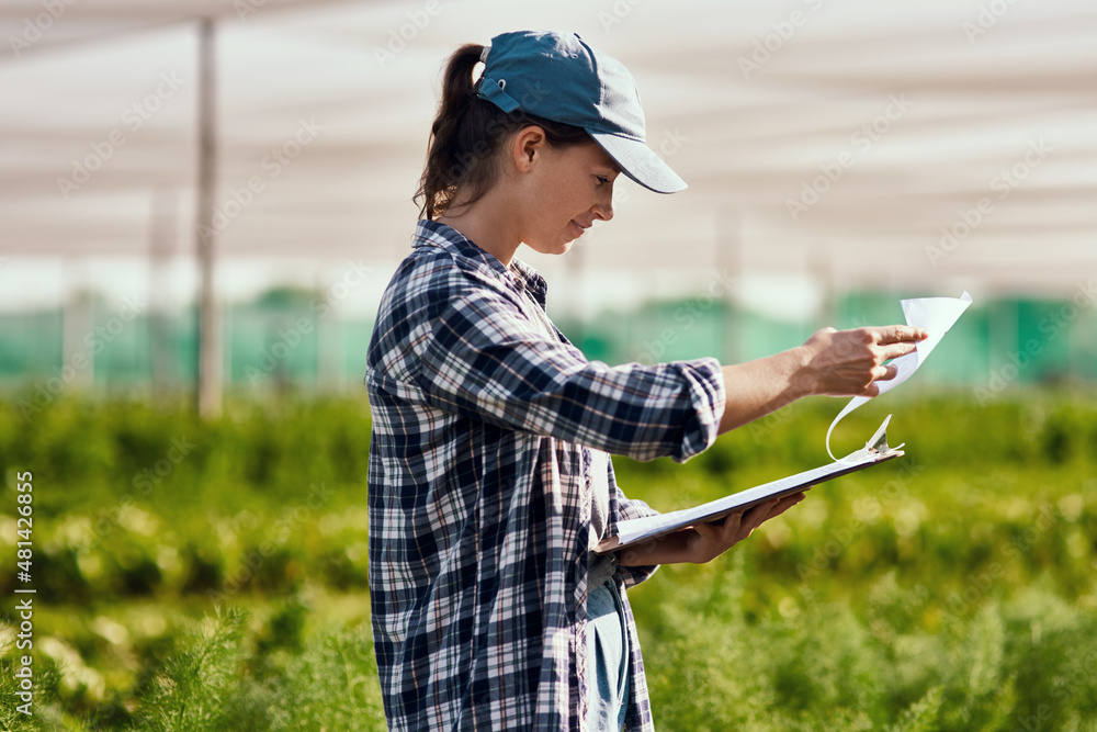 These numbers look promising. Cropped shot of an attractive young female farmer looking over paperwo