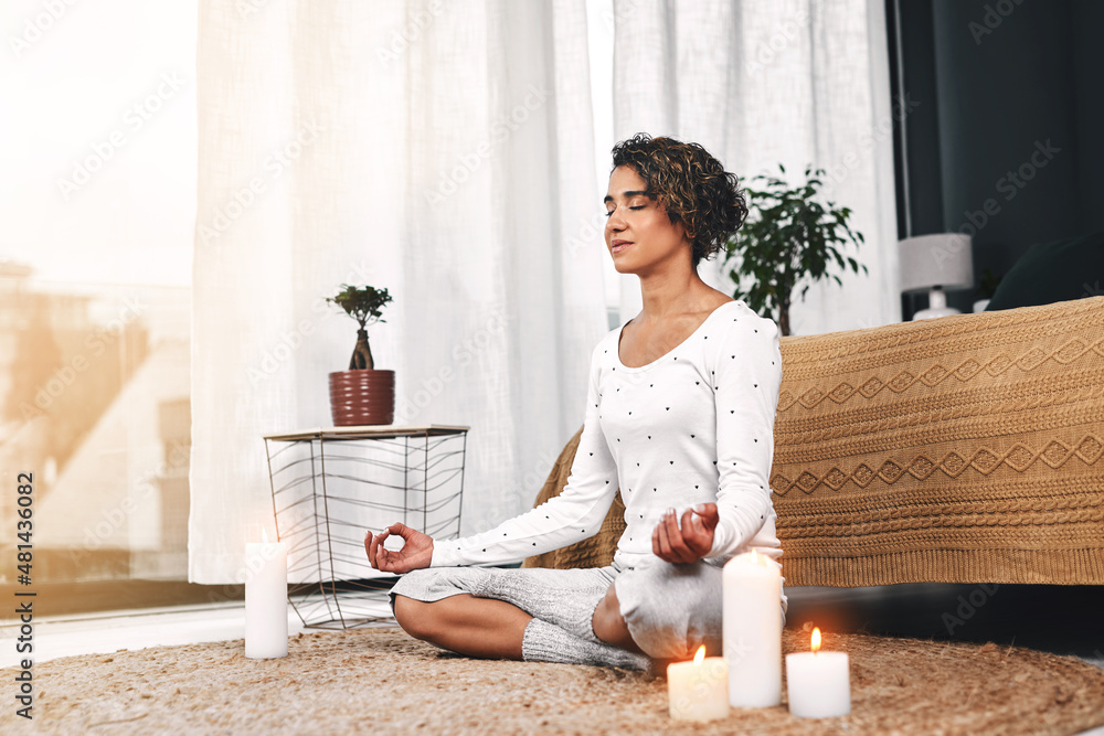 Scented candles help me relax. Full length shot of an attractive young woman sitting and meditating 