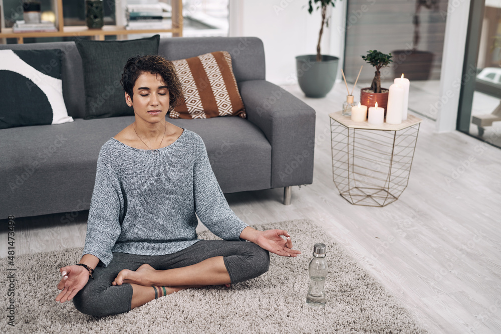 Lifestyle revised. Shot of an attractive young woman meditating on the lounge floor at home.