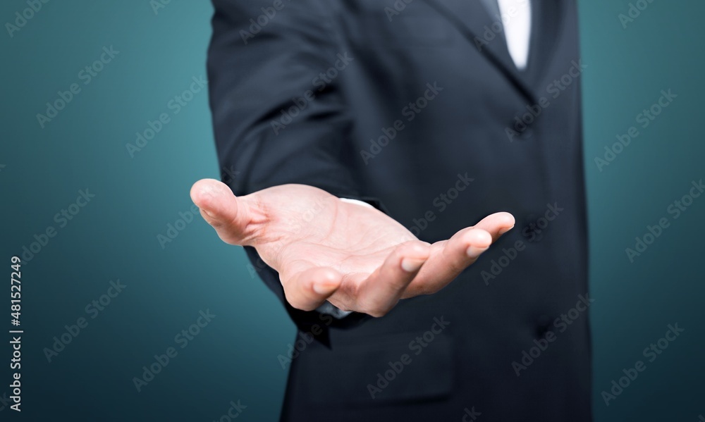 Male hand in a suit shows a palm up gesture on a background.