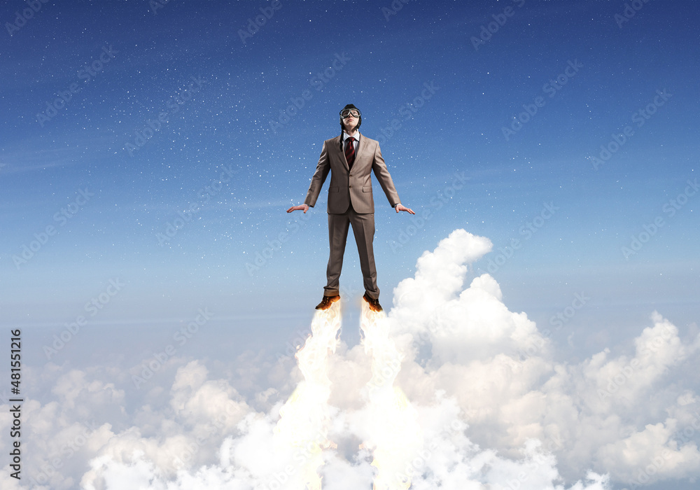 Businessman in suit and aviator hat flying in sky