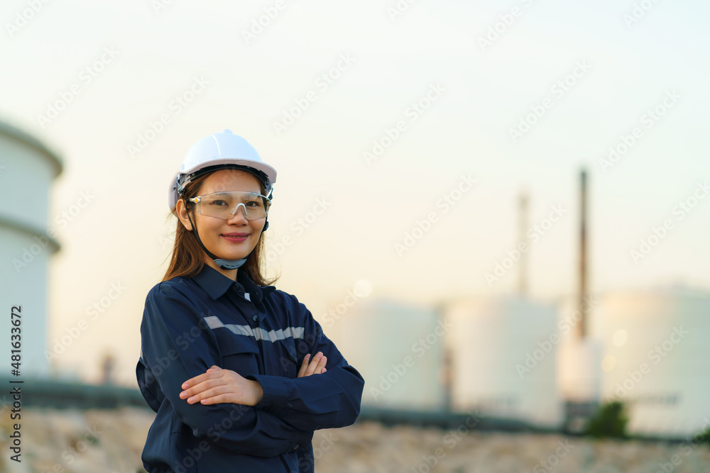 Asian woman engineer arm crossed and smile with confident looking forward to future with oil refiner