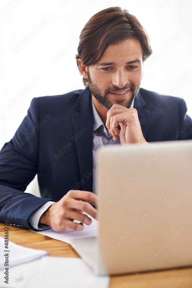 Turning paperwork into profit. A handsome businessman working on his laptop at his desk.