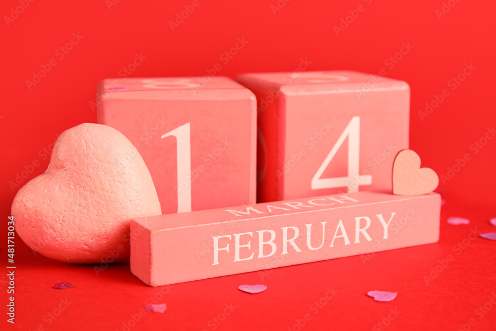 Calendar with date of Valentines Day and plastic heart on red background