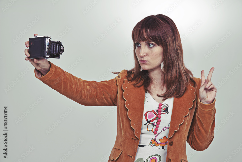 The seventies selfie. Cropped studio shot of a young woman in a vintage outfit taking a selfie with 