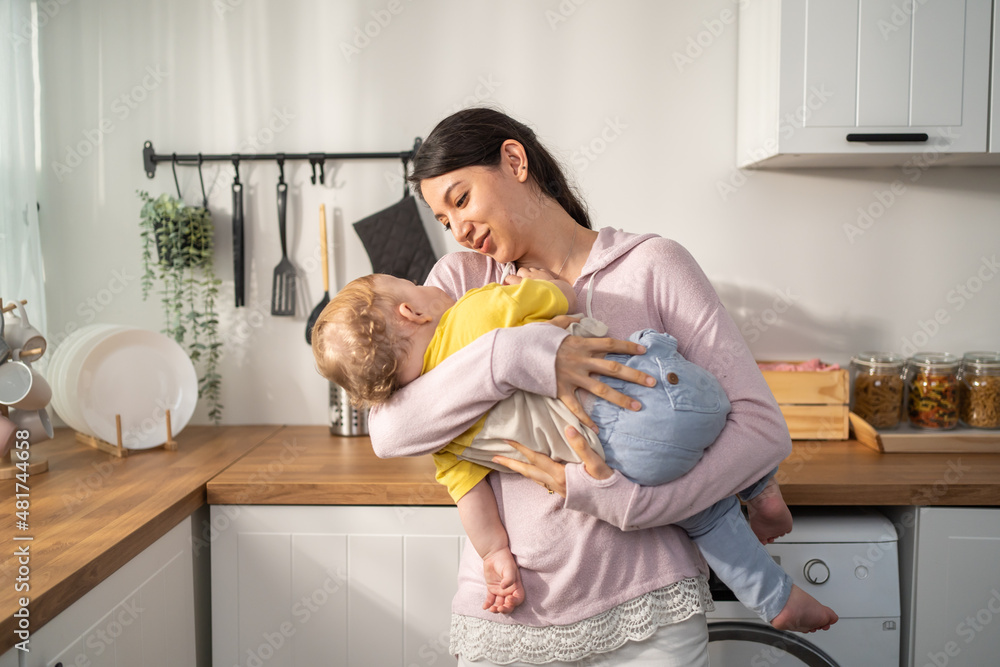 Caucasian loving mother hold baby boy toddler to lull him to sleep. 