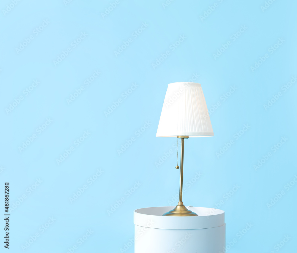 Table with stylish lamp on color background