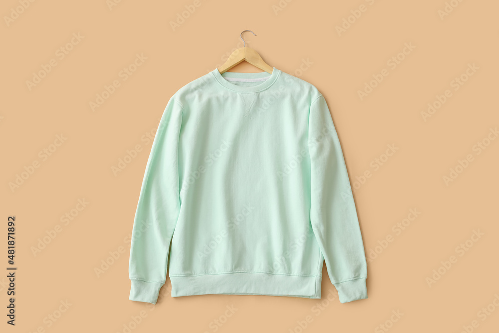 Stylish blue sweatshirt on beige background