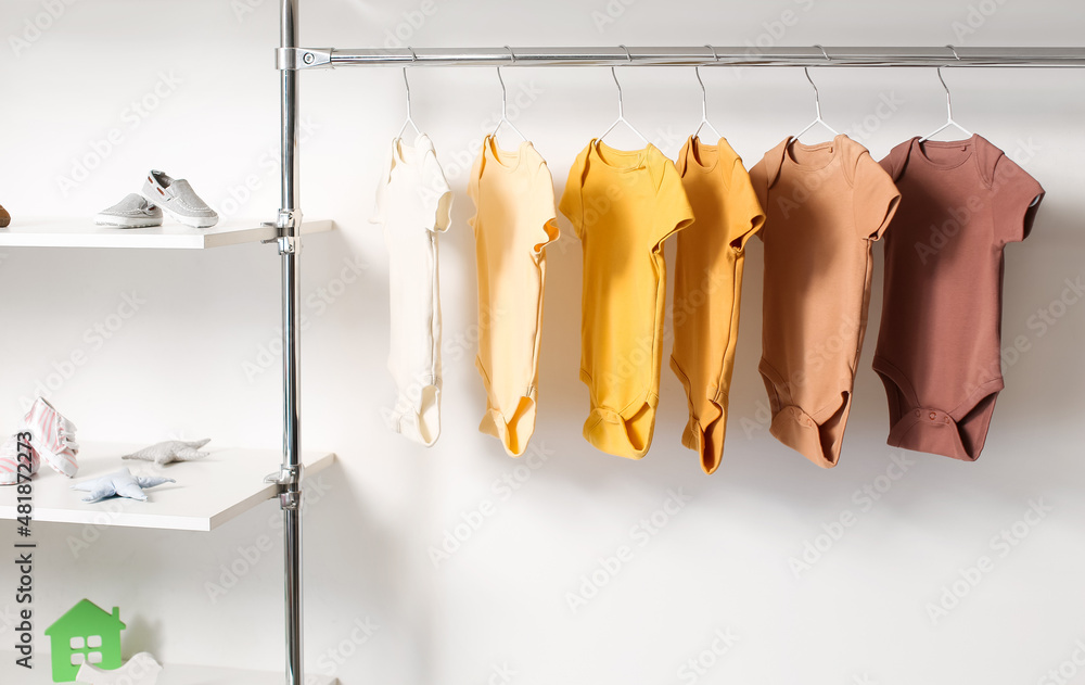 Baby bodysuits hanging near light wall in room