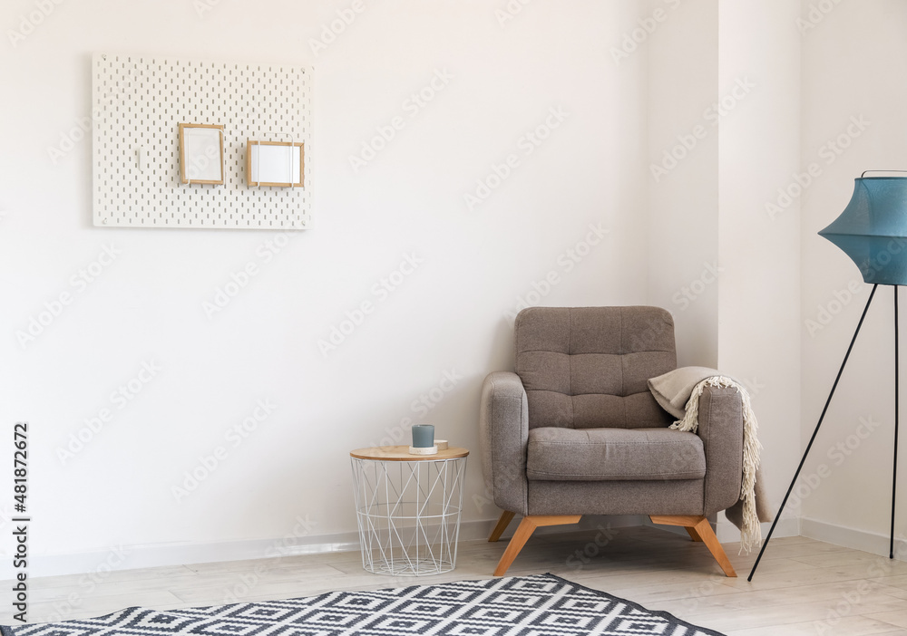 Interior of light living room with soft armchair, table and pegboard