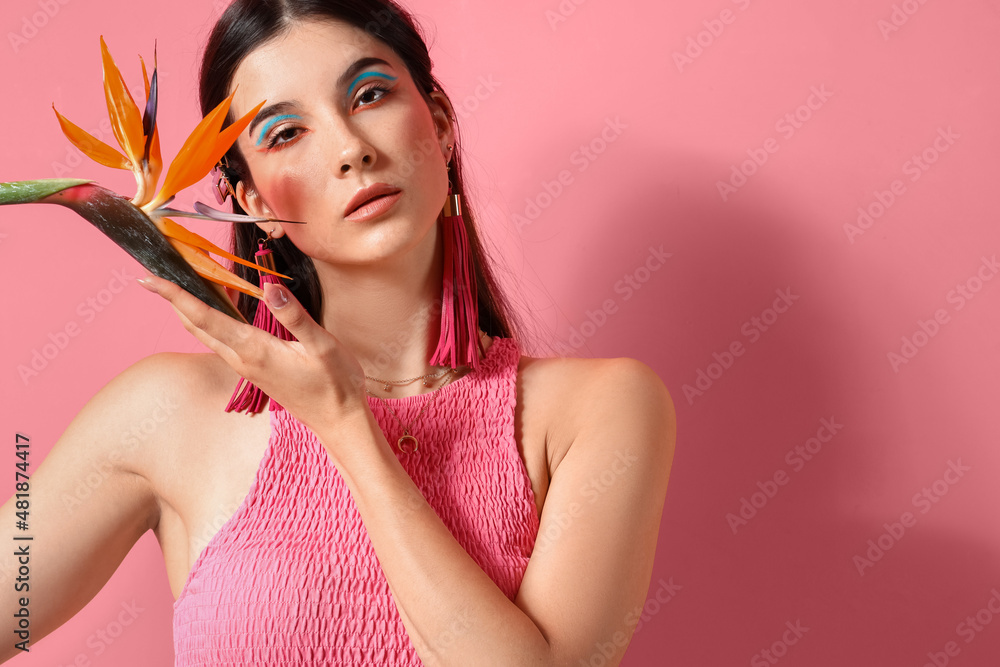 Beautiful young woman with strelitzia flower on color background