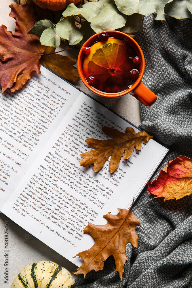 Book, cup of tea and autumn decor on light background