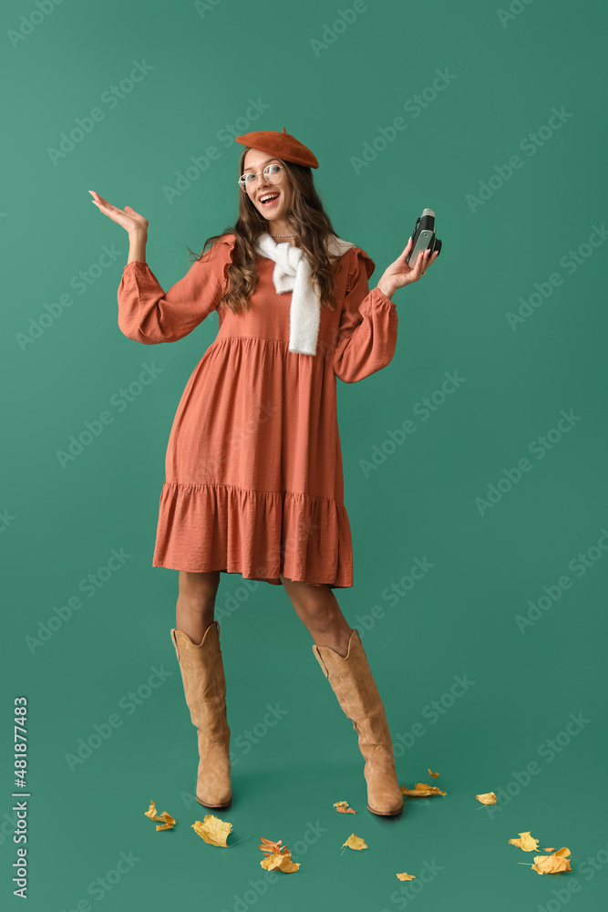 Happy Parisian woman with vintage photo camera on green background