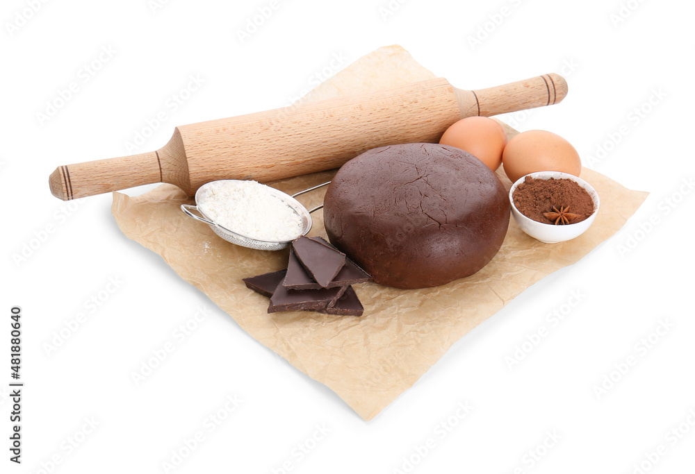 Baking parchment with ingredients for preparing tasty cookies and rolling pin on white background