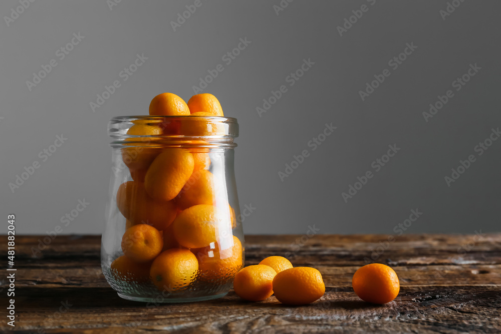 Jar with tasty kumquat fruits on wooden table