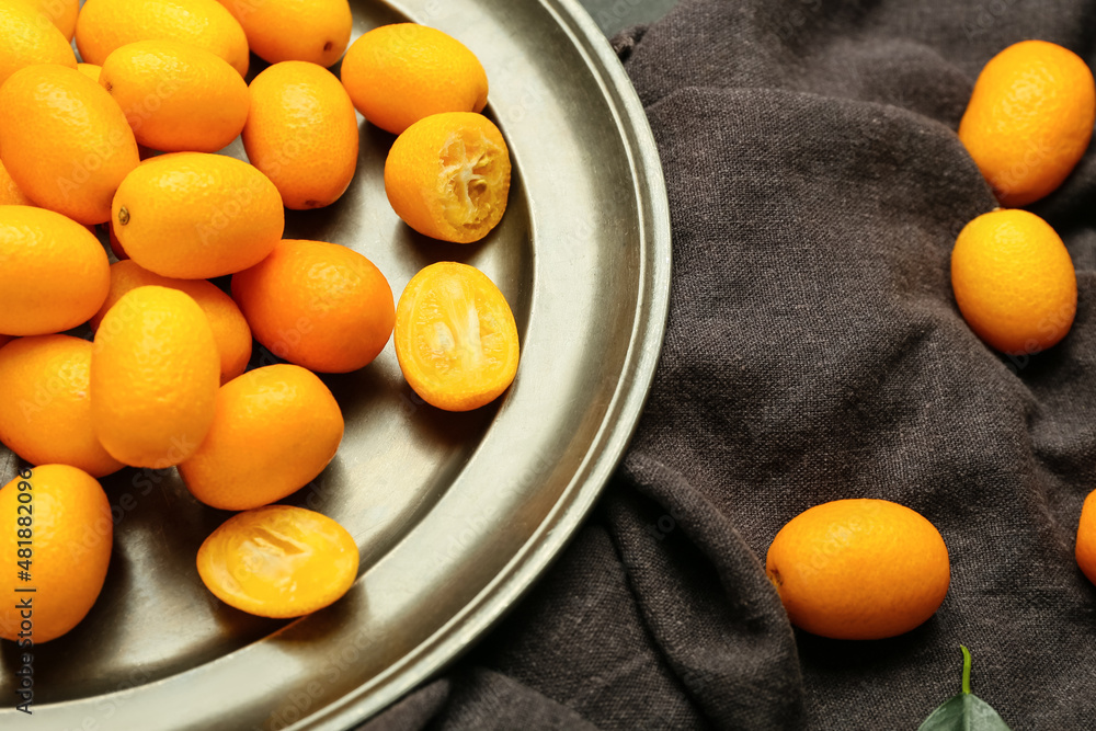 Plate with tasty kumquat fruits on dark background