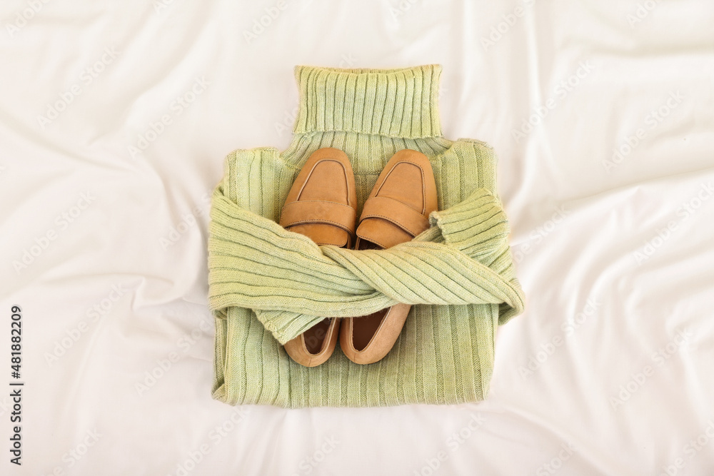 Knitted roll-neck sweater and shoes on crumpled fabric background