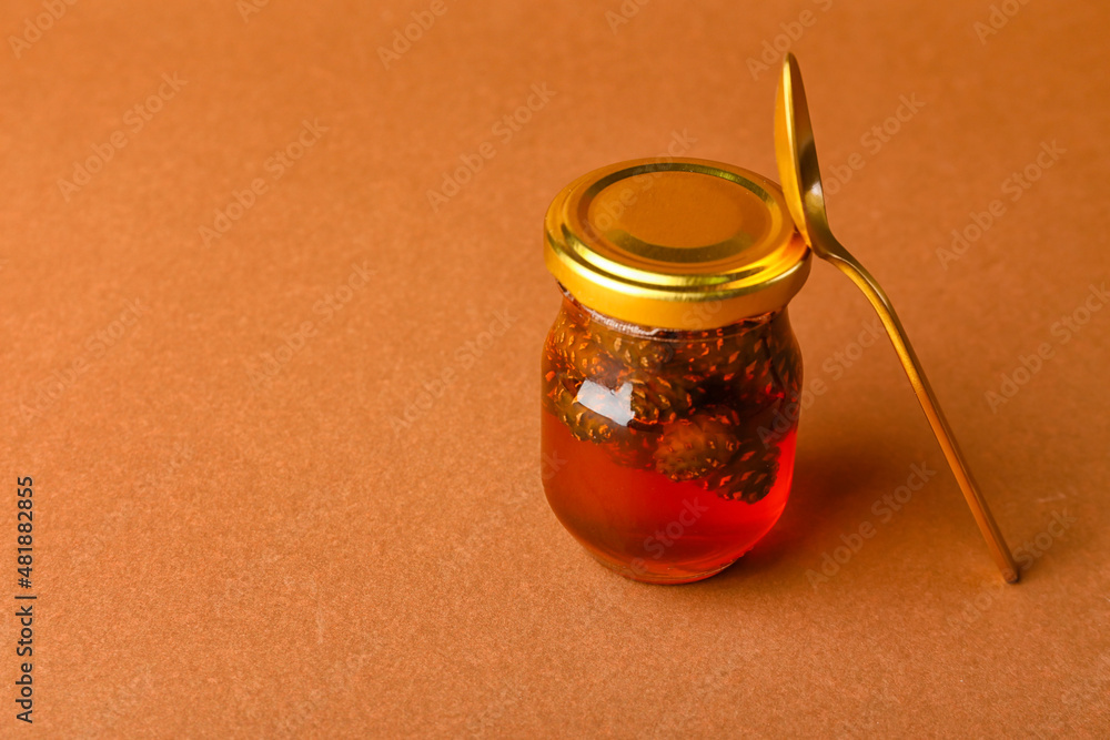 Jar of tasty pine cone jam on color background