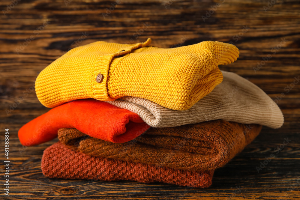 Stylish baby sweaters on wooden background