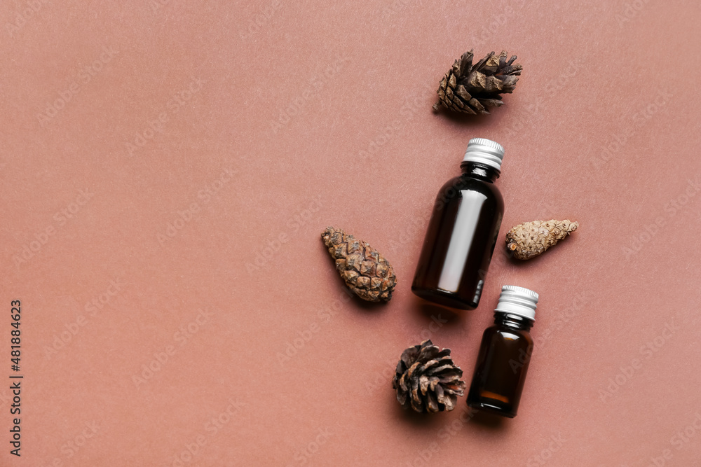 Bottles of essential oil and cones on color background