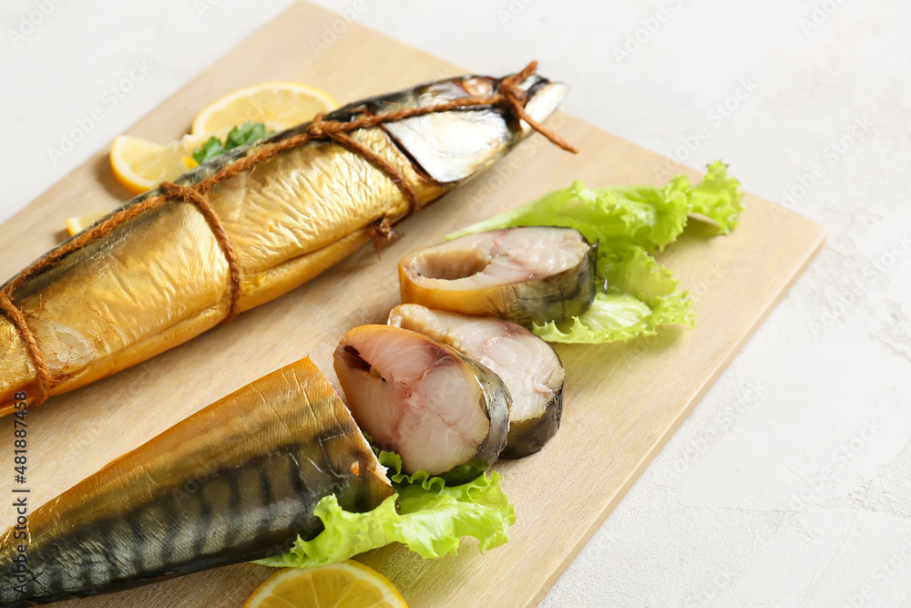 Wooden board with smoked mackerel fishes on light background, closeup