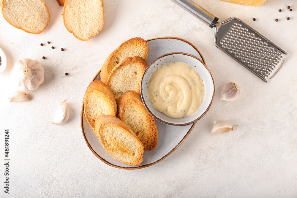 Plate of tasty croutons and bowl with sauce on white background