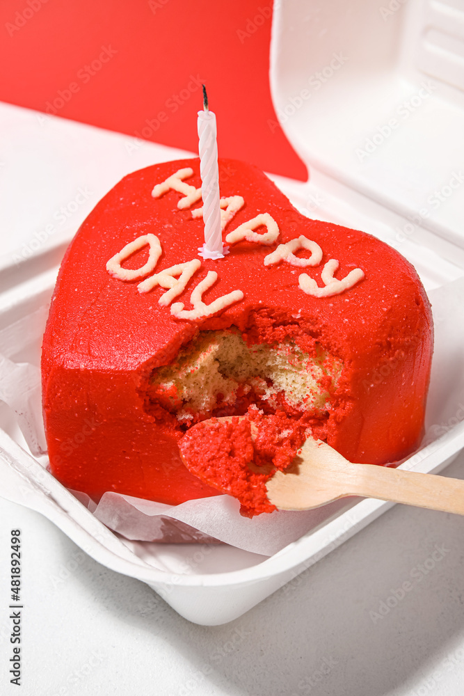 Plastic lunch box with tasty bento cake and candle on color background, closeup