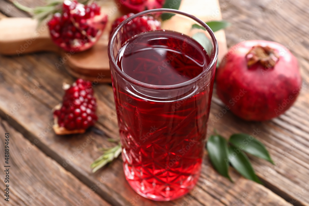 Glass of delicious pomegranate juice on wooden background