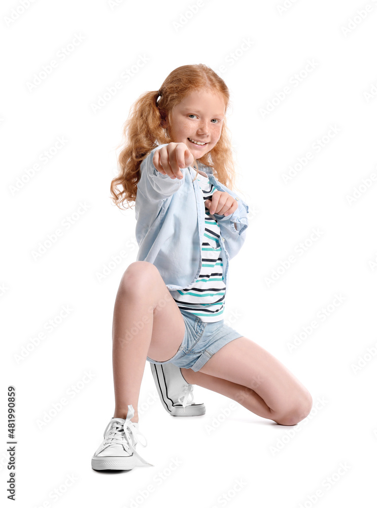 Little redhead girl with ponytails pointing at viewer on white background