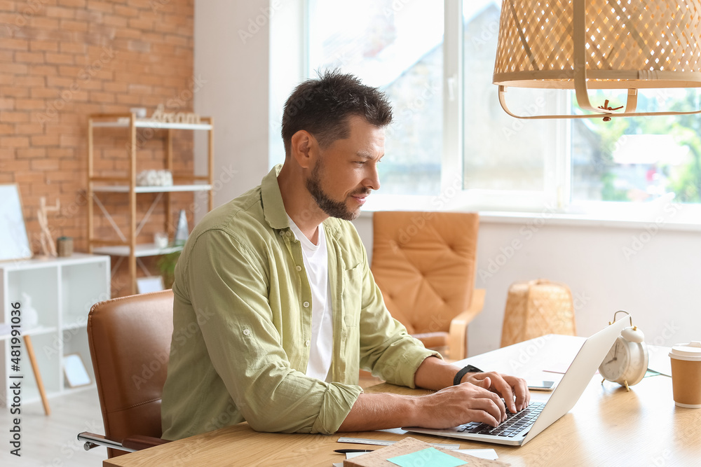 Handsome man working with laptop at table in office